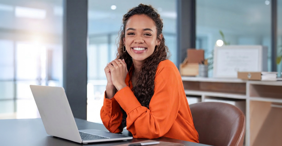 A young female sits at her desk, smiling at the opportunities provided through young talent programmes