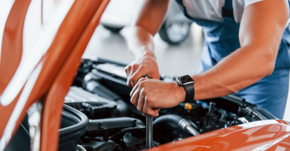 A man works on an orange car, illustrating the need for clarity on extended car warranty