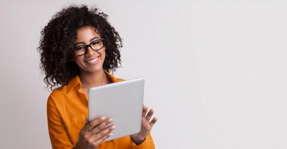 A female where an orange top and using her tablet to save on her car insurance premiums online