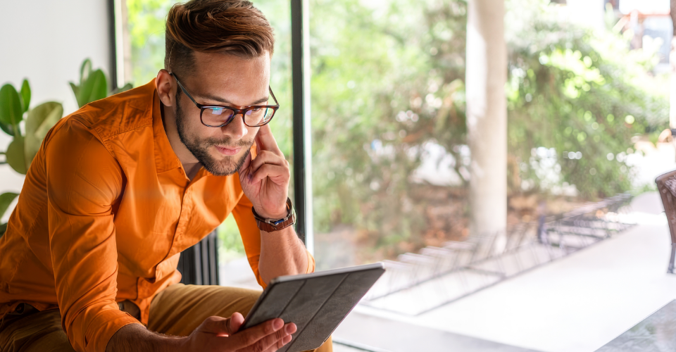 A man uses his tablet to research the difference between direct insurance vs a broker