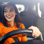 A female smiling as she drives the car