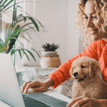 A women with a dog on her lap researching and comparing pet insurance plans in SA on her laptop